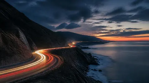 作品の見本: 夜の海沿いの道を走る車の光跡